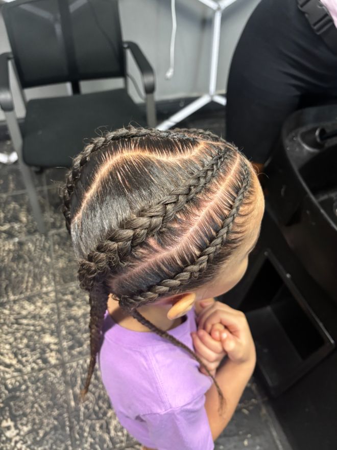 A young girl with cornrows braided in curved rows, seen from the side.