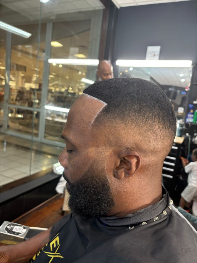 Side view of a man with a full beard and a sharp square hairline after a cut.