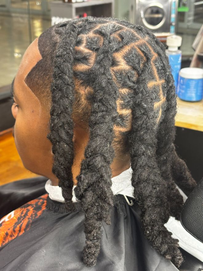 The back of a head of locs styled in a barrel pattern above a faded neckline.